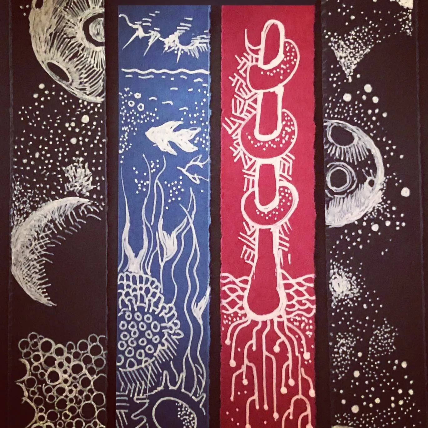 Four painted bookmarks side by side, decorated in white ink with moons, a koi fish among water weeds, and a red strip of linked rings.