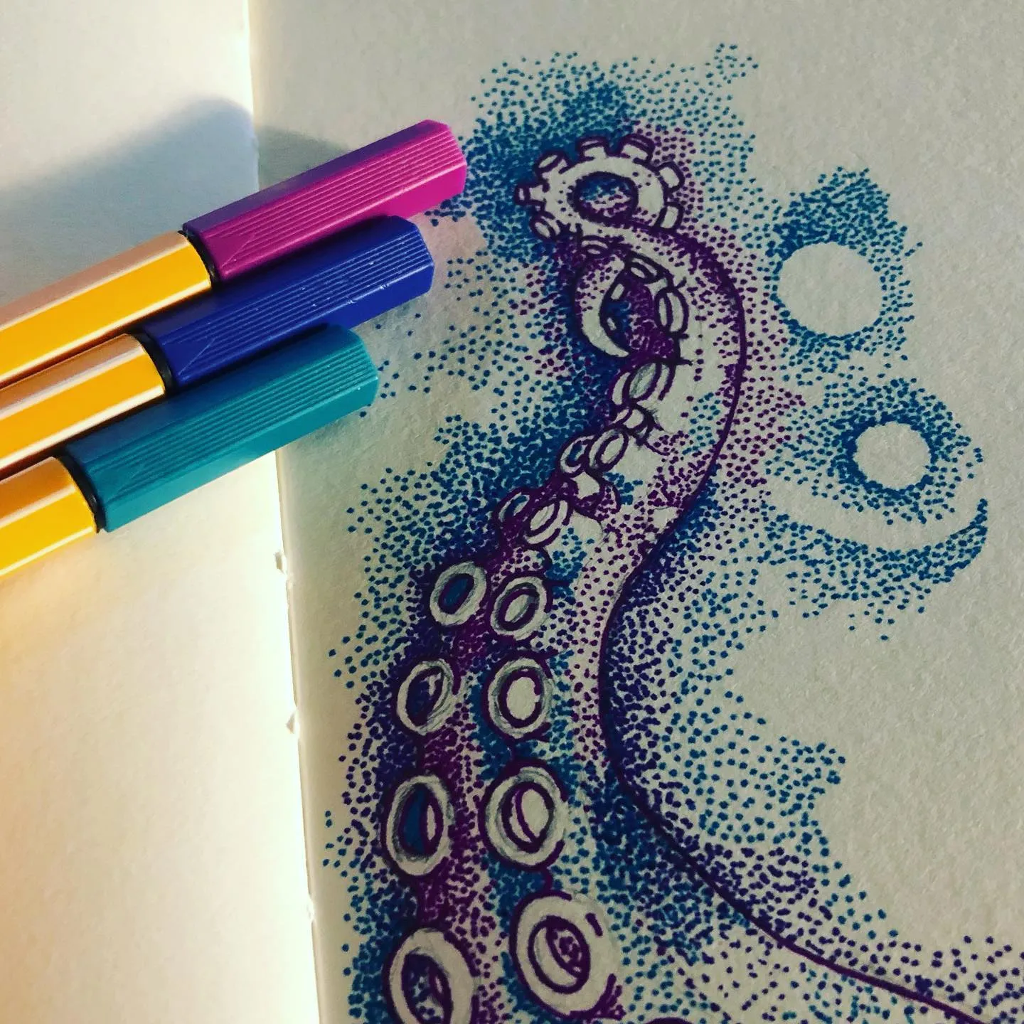 Stippled ink tentacle curling up the page in purple and blue dots, with round bubbles beside it and coloured fineliners lying nearby.