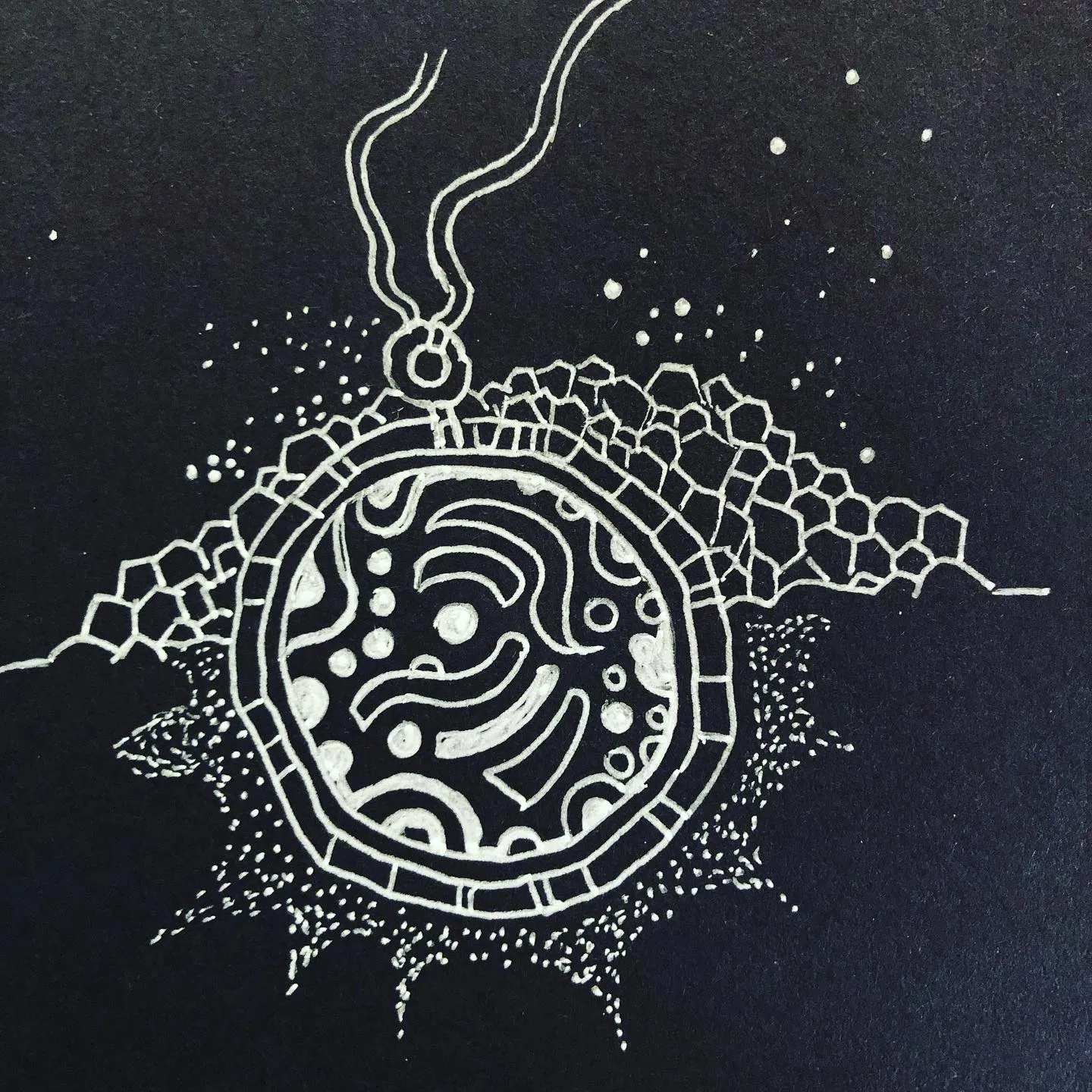 White ink on black paper: a round, maze-patterned amulet on a chain, surrounded by hexagons and scattered dots.