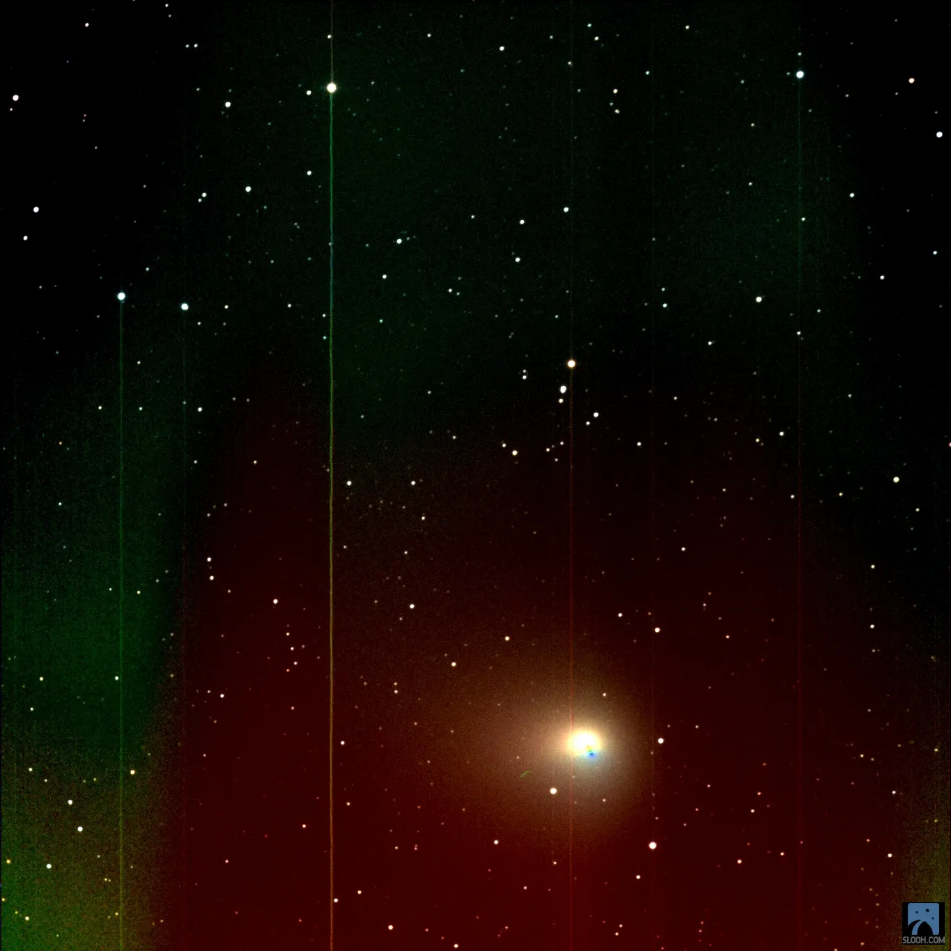 The comet as a bright point inside a haze of red and green streaks.