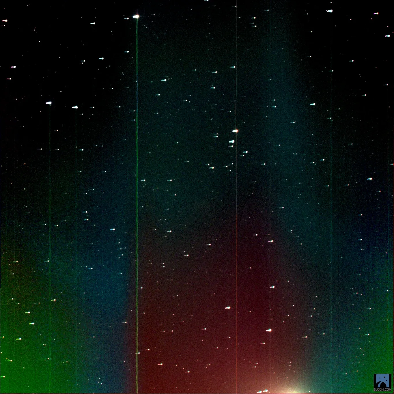 The comet glowing at the bottom of the frame, behind bands of red, green and blue left by the telescope's colour filters.