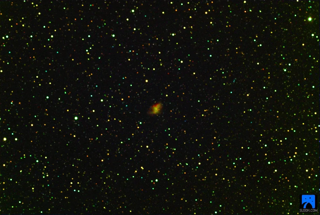 The Crab Nebula (M1), a small orange smudge among coloured stars.
