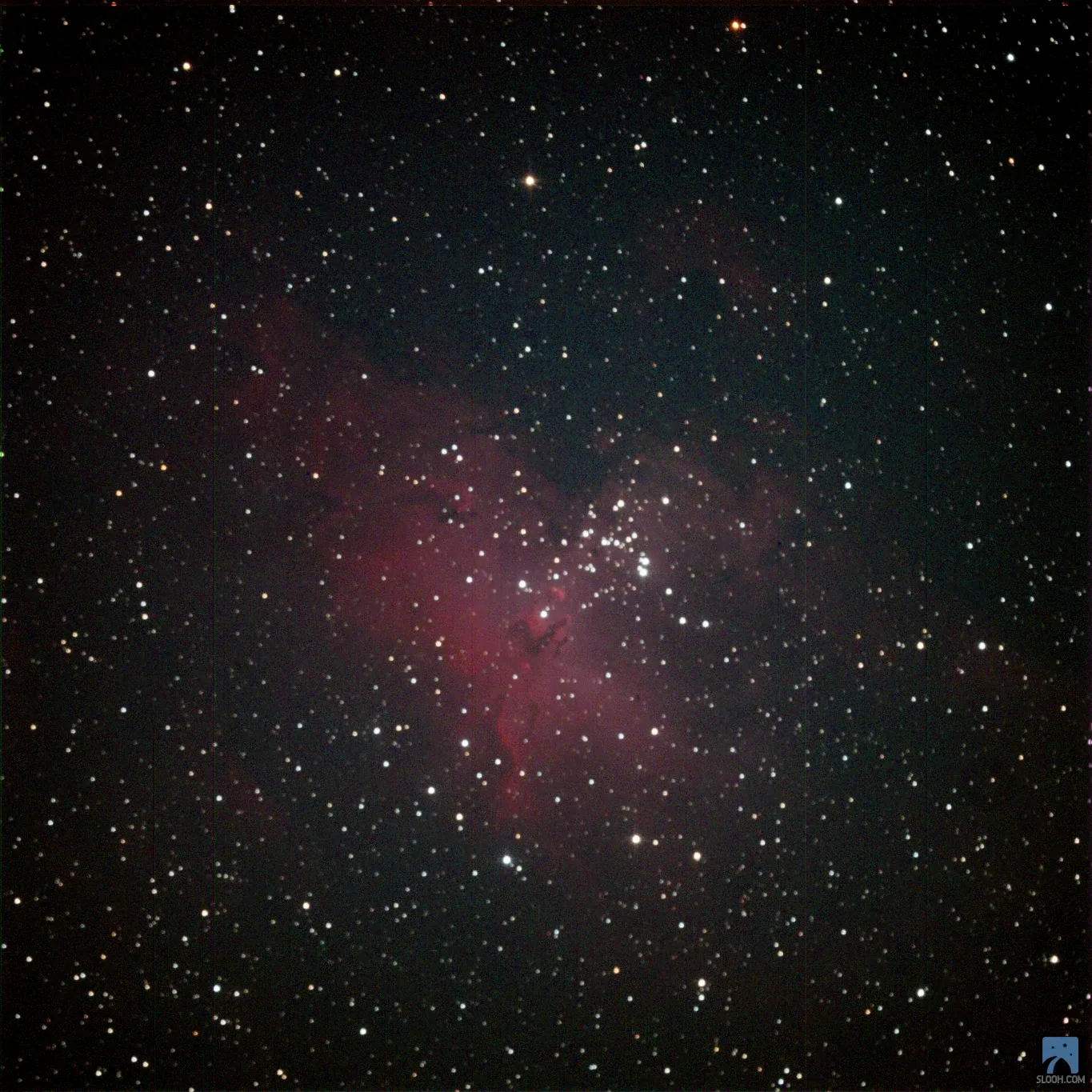 The Eagle Nebula (M16): red clouds of gas around a cluster of stars.