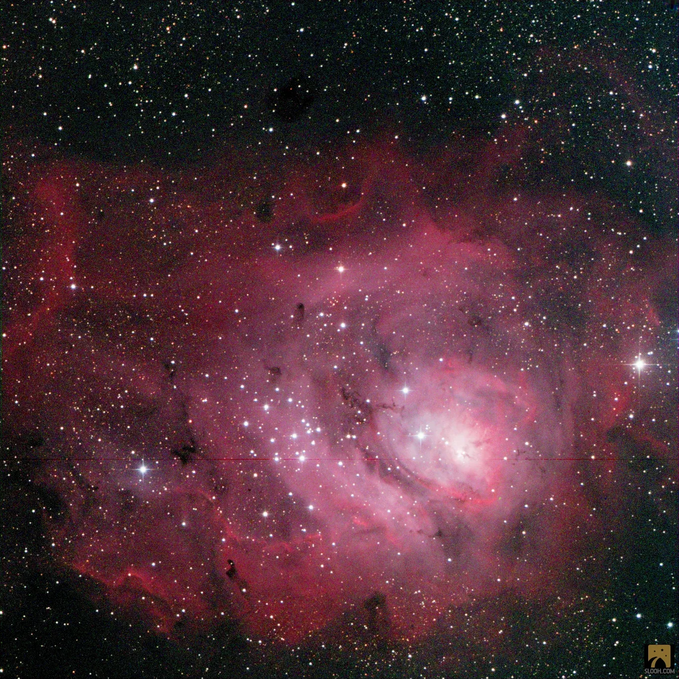 The Lagoon Nebula (M8): clouds of glowing pink and red gas around a cluster of bright stars.